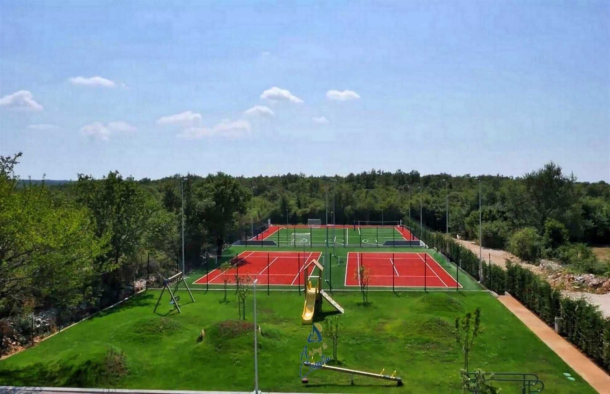 A tennis court complex with multiple courts, a children's play area, and surrounding greenery.