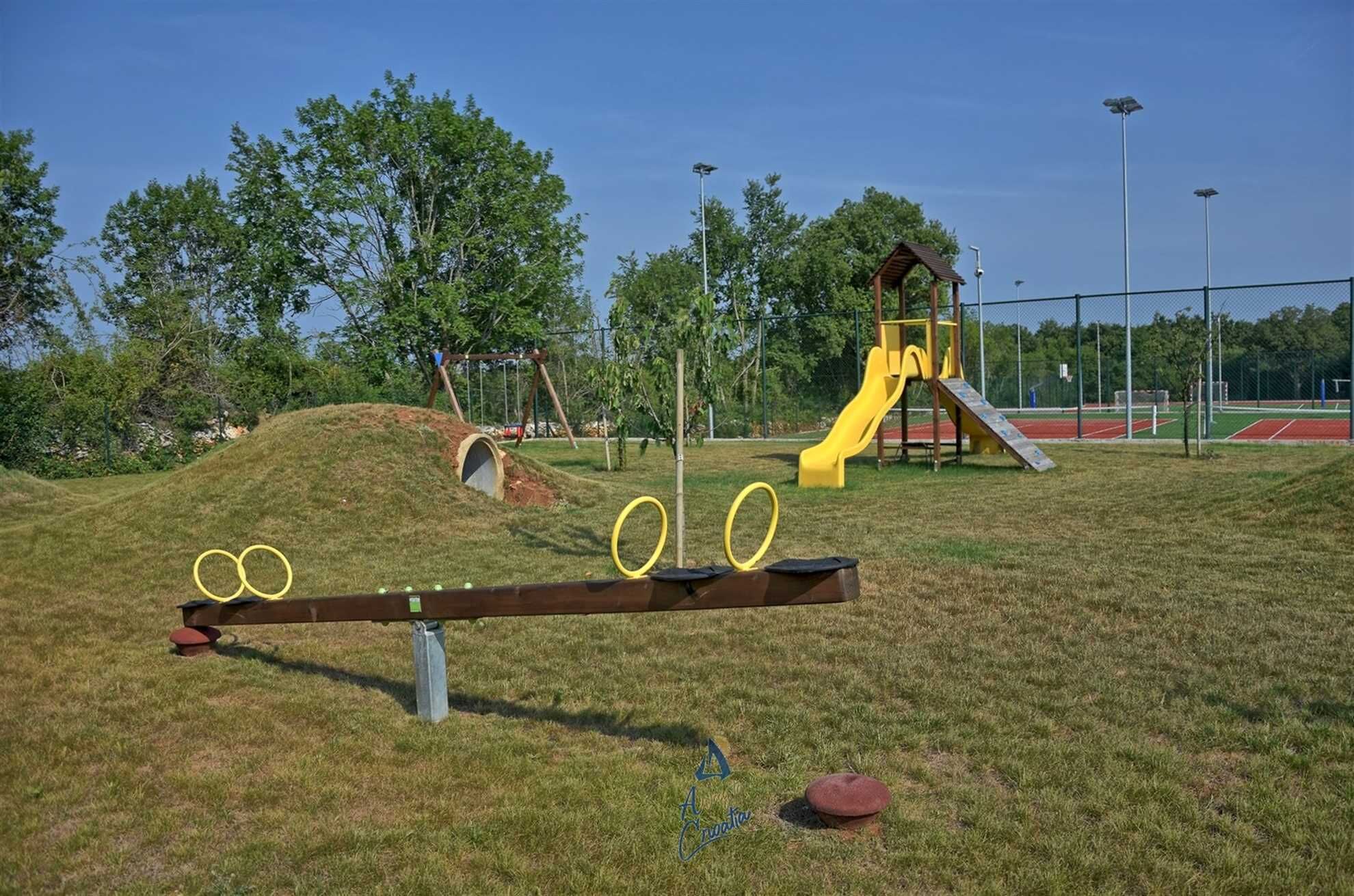Ein Spielplatz mit einer Wippe, einer Rutsche und einer Kletterkonstruktion.