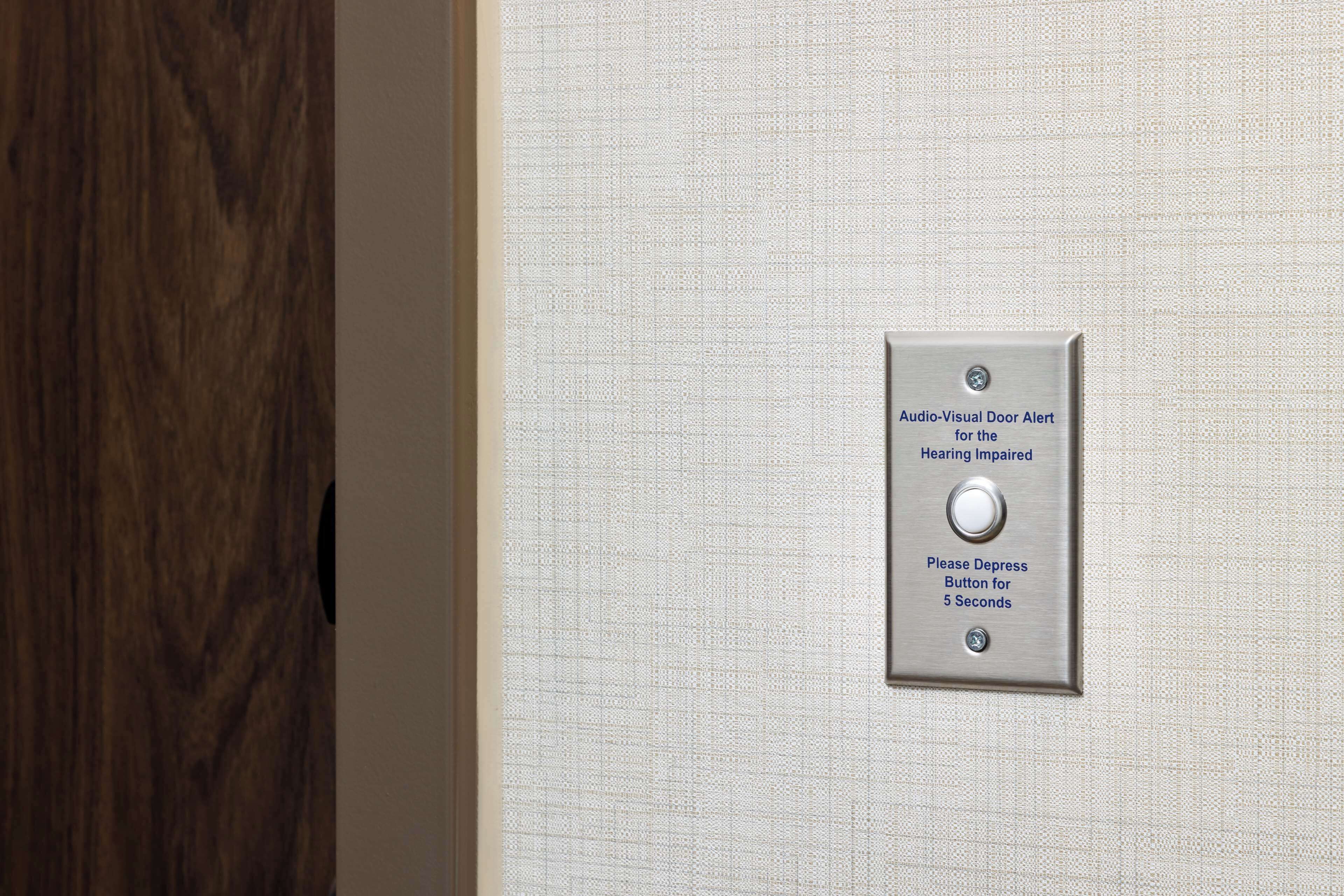 A door with a textured wall and a metal plate with instructions for the hearing impaired.