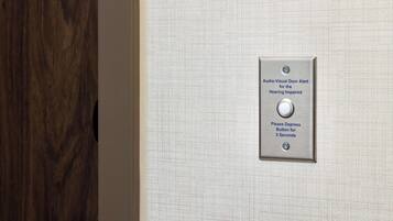 A door with a textured wall and a metal plate with instructions for the hearing impaired.