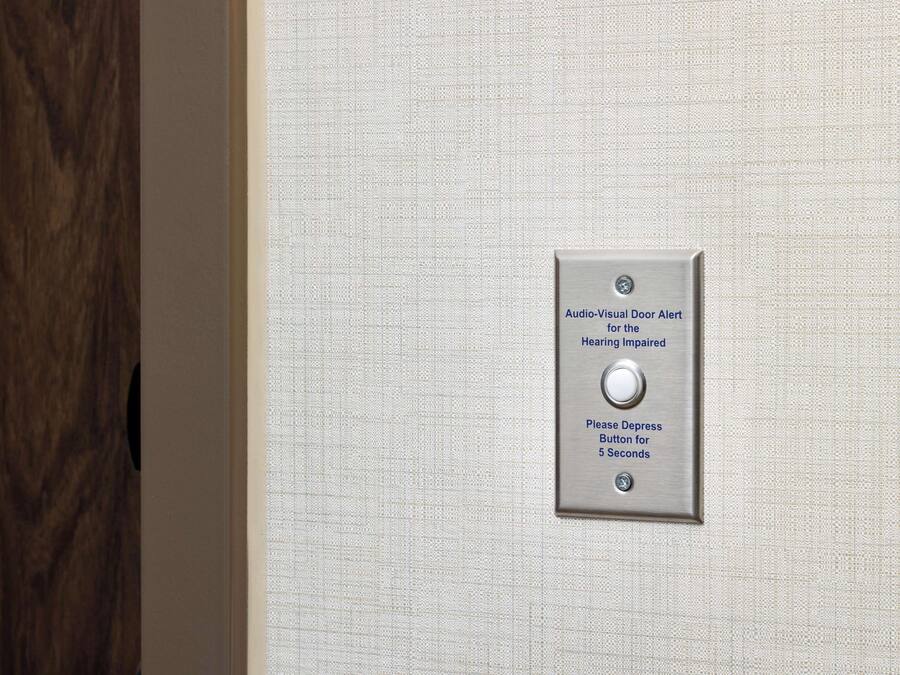 A door with a textured wall and a metal plate with instructions for the hearing impaired.