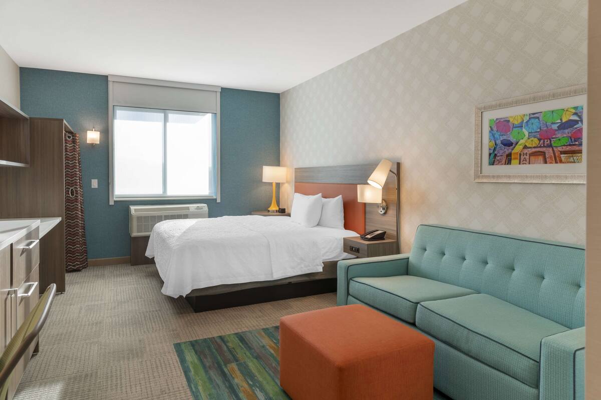 Una habitación de hotel con una cama, un sofá, un escritorio y una ventana.