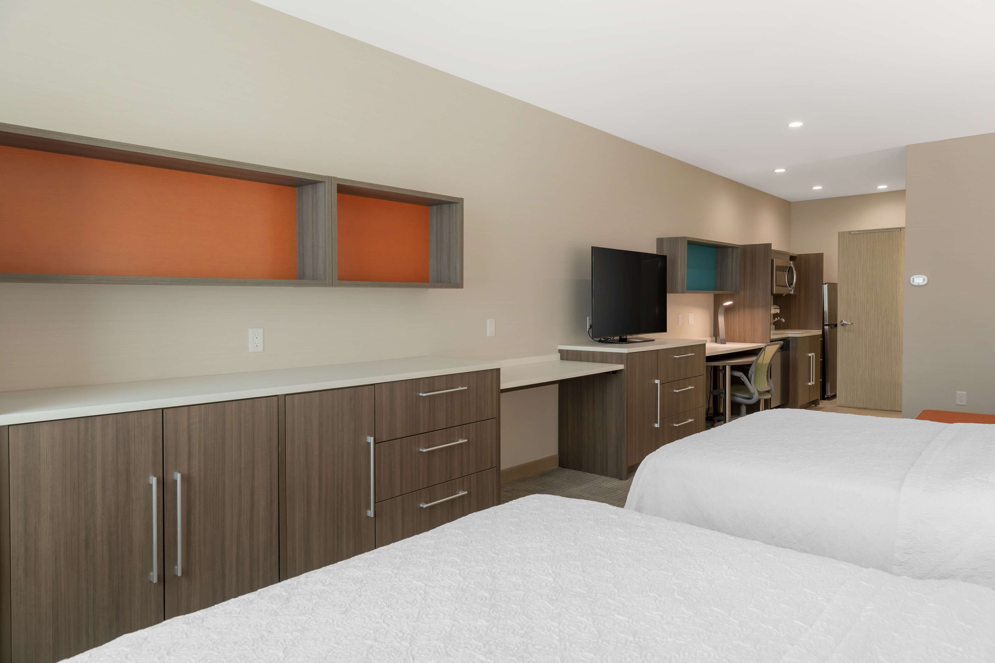 Een moderne hotelkamer met een kitchenette, een flatscreen televisie en een bed.