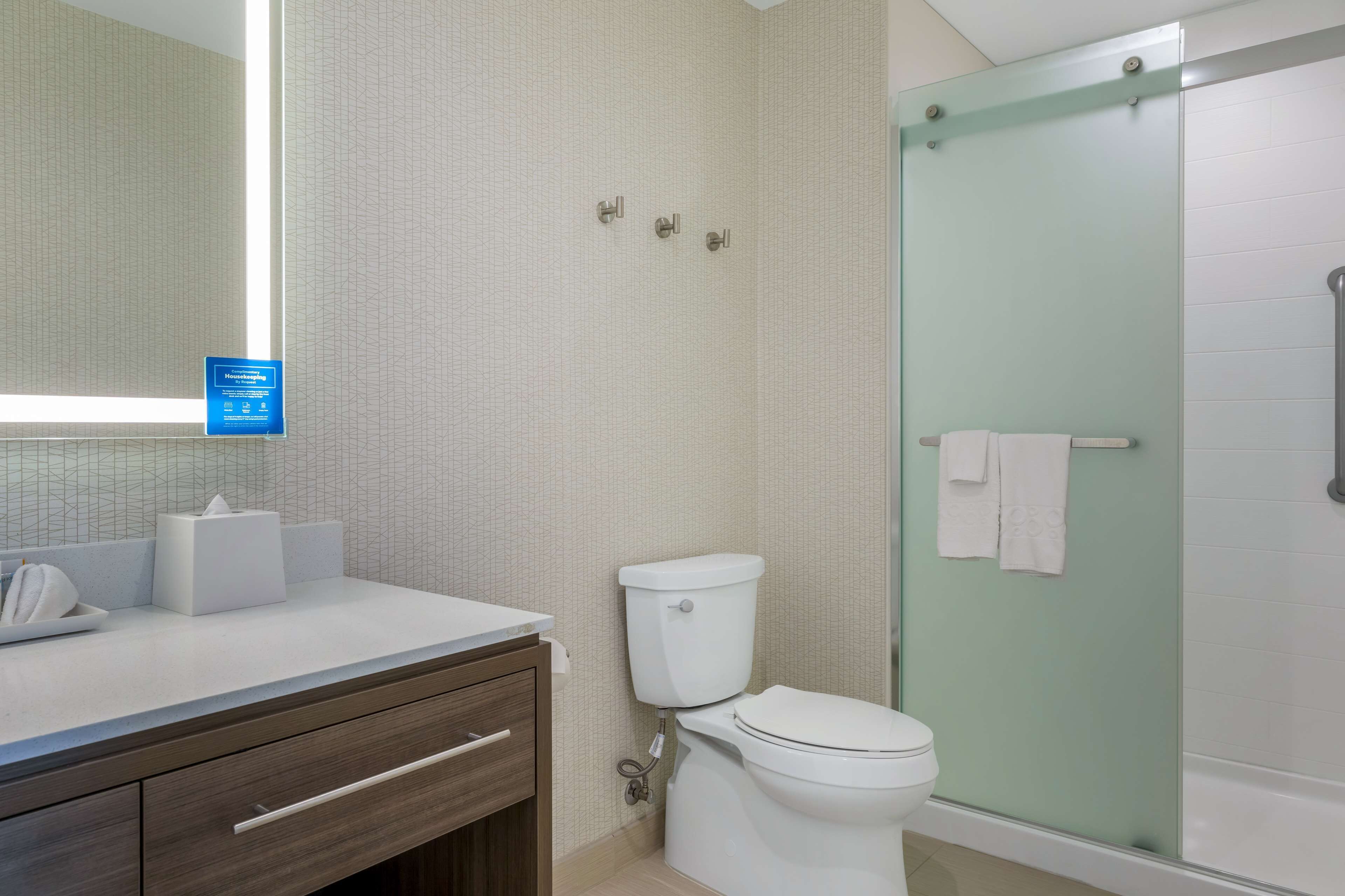 Un baño con inodoro, lavamanos con espejo y cabina de ducha de vidrio.
