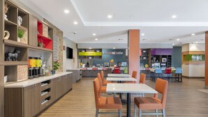 Un restaurant moderne avec des meubles en bois, des chaises orange et un comptoir où sont exposés divers articles.