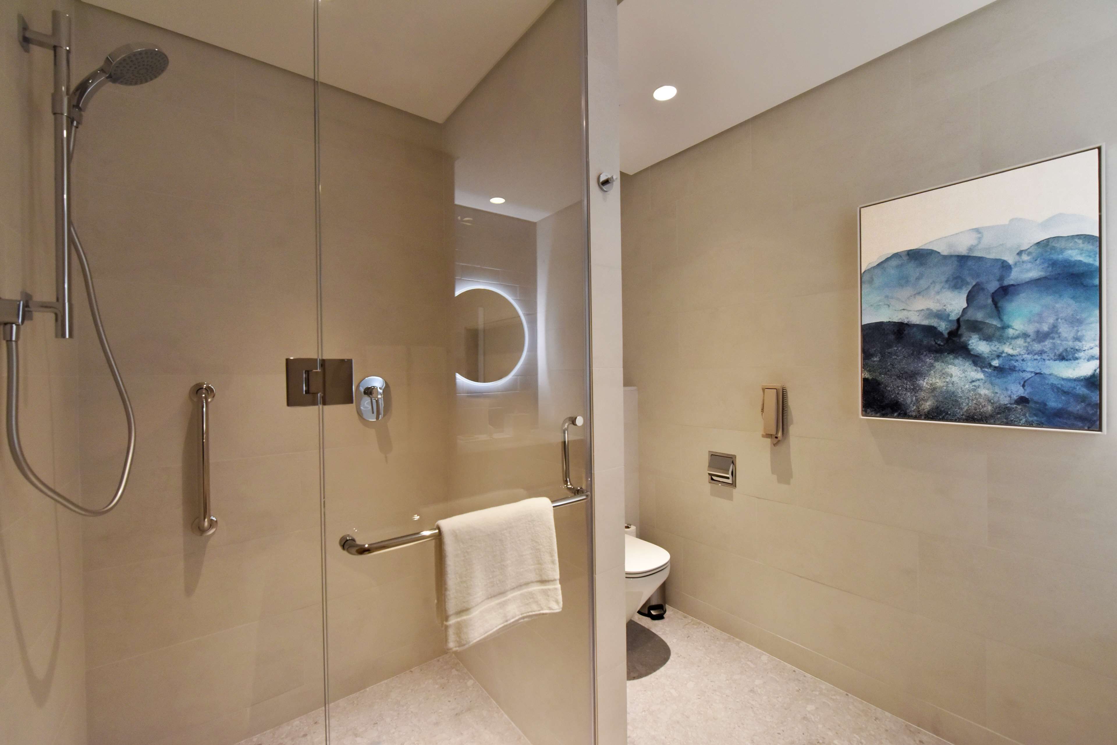 A modern bathroom with a glass-enclosed shower, a toilet, and a wall-mounted sink.