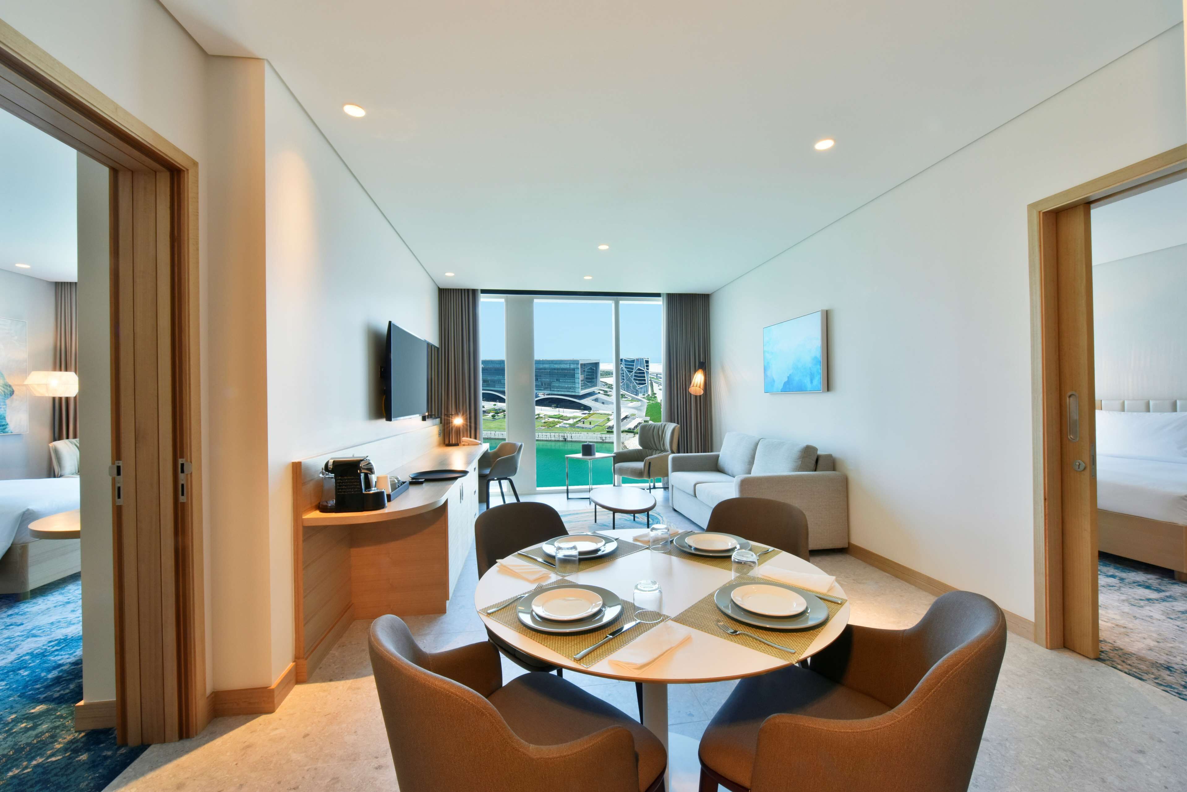 Habitación de hotel con comedor, sofá, cama y vistas a la ciudad.