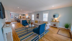A spacious living area with a sofa, chairs, a coffee table, and a kitchen in the background. - Blue Haven Home, Fire Pit & Blocks from Beach (Cape Charles)