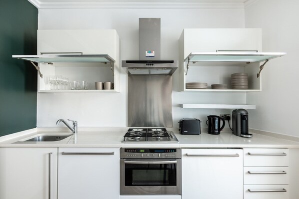 A modern kitchen with a gas stove, oven, and a coffee maker.