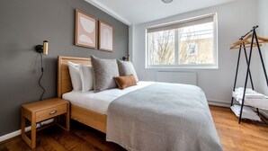 Une chambre à coucher comprenant un lit, une table de chevet, une lampe et une fenêtre donnant sur des arbres.