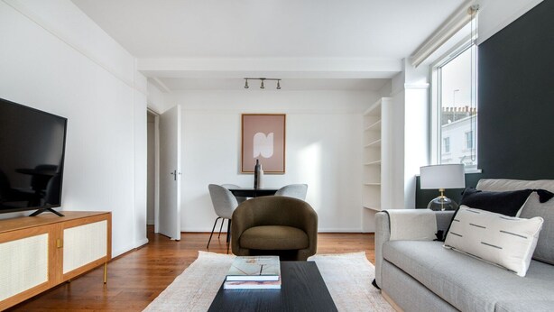 Un salon moderne doté d’un téléviseur à écran plat, d’un canapé, d’une table basse et d’un coin repas avec des chaises.