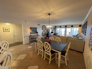 A dining area with a table and chairs, a sofa, and a chandelier. - "Breakers East 902" Gulf Front 2 BR/2BA Beach setup included (Destin)