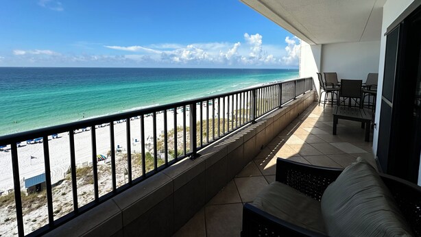 A balcony with a view of the ocean, a beach, and a seating area with chairs and a table. - "Breakers East 902" Gulf Front 2 BR/2BA Beach setup included (Destin)