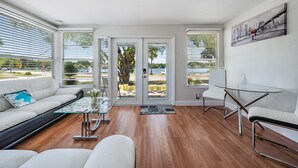 Ein modernes Wohnzimmer mit Glastisch, weißem Sofa und Glastisch-Esstisch.