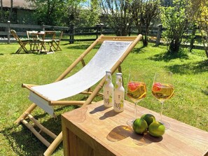 A wooden deck with a lounge chair, two bottles labeled 'hug,' two glasses of wine, and three limes.