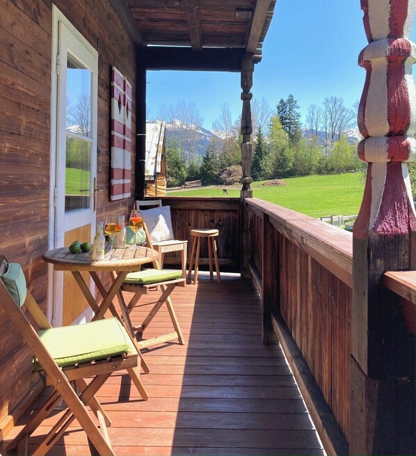 A wooden deck with a table, chairs, and a painting on the wall.