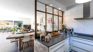 A modern kitchen with a large island, white cabinetry, and a view of the outdoor patio. - Superb contemporary villa PIED DANS L'EAU - plage de l'Ayguade / with plancha (Hyères)