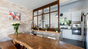 A modern kitchen with a wooden dining table, white cabinets, and a built-in oven. - Superb contemporary villa PIED DANS L'EAU - plage de l'Ayguade / with plancha (Hyères)
