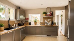 Een moderne keuken met roestvrijstalen apparatuur, een groot eiland en uitzicht op de omgeving.