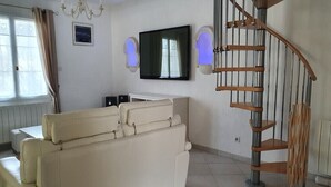 Ein Wohnzimmer mit einer Couch, einem Fernseher und einer Wendeltreppe.