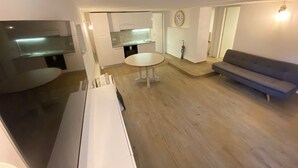 Een compacte leefruimte met een kitchenette, een eettafel en een bank.