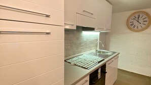 Een moderne keuken met witte kasten, een roestvrijstalen aanrecht en een inbouwoven.