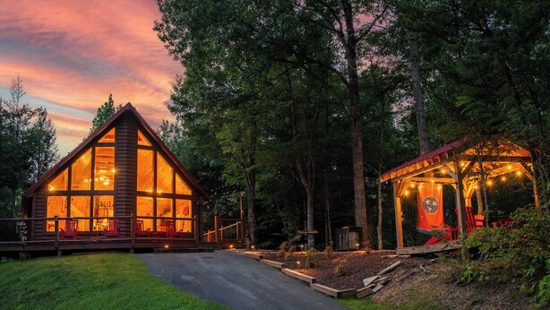 Een chalet met grote ramen, een terras en een overdekte zitplek buiten.