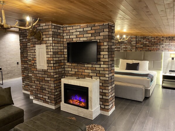 A modern living room with a brick fireplace, a flat-screen TV, and a cozy seating area. - Elifim Resort Hotel (Gerede)
