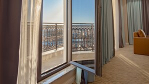 Ett hotellrum med ett stort fönster, en bänk och utsikt över stadsbilden.