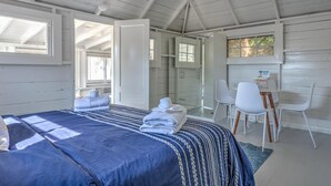 A bedroom with a bed, a desk, and chairs. - Bungalow 1 - 1br, Water View (Westhampton Beach)