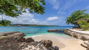 A beach with clear turquoise water, a wooden pier, and a gazebo. - Seagrapes Villa (Discovery Bay)