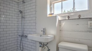 A bathroom with white tiled walls, a white sink, and a toilet. - Bungalow 2 - 1br, Water View (Westhampton Beach)