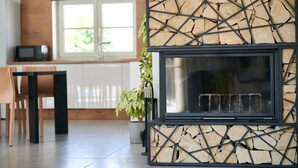 A modern living room with a stone fireplace, a dining area with a table and chairs, and a large window providing natural light. - Lovely Villa Gemini with a swimming pool (Visnjan)
