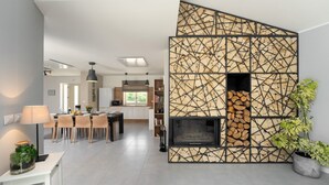 A modern kitchen with a built-in fireplace, a dining area with a table and chairs, and a living space with a sofa and a potted plant. - Lovely Villa Gemini with a swimming pool (Visnjan)