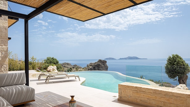 A poolside area with a view of the sea, a wooden table, and a sofa. - Stunning sea views, access to a private cove, hot tub! (Rethymno)