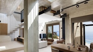 A modern interior with a dining area, a living space with a TV, and a staircase leading to an upper level. - Stunning sea views, access to a private cove, hot tub! (Rethymno)