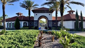 Un edificio con un arco central, rodeado de palmeras y un jardín cuidado.