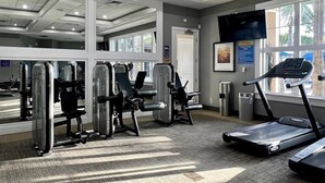 Un gimnasio con equipo de ejercicio, una cinta de correr y amplios ventanales.