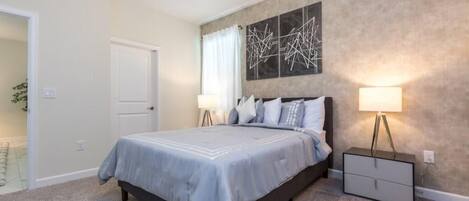 A bedroom with a bed, bedside lamps, a nightstand, and a wall art piece.