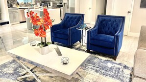A modern living room with two blue armchairs, a white coffee table, and a vase of red flowers. - HEART OF MIAMI LUXURY HOME 4BR 3.5BA POOL 5MIN BEACH (Miami)