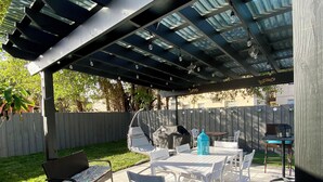 An outdoor patio with a covered seating area, a table, and chairs. - HEART OF MIAMI LUXURY HOME 4BR 3.5BA POOL 5MIN BEACH (Miami)