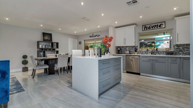 A modern kitchen with grey cabinets, a central island, and a dining area with a table and chairs. - HEART OF MIAMI LUXURY HOME 4BR 3.5BA POOL 5MIN BEACH (Miami)
