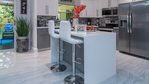 A modern kitchen with white cabinets, stainless steel appliances, and a central island with bar stools. - HEART OF MIAMI LUXURY HOME 4BR 3.5BA POOL 5MIN BEACH (Miami)