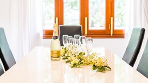 A dining table with a bottle of champagne, glasses, and a floral arrangement. - House Sa Dalia very close to Alcudia Beach (Alcúdia)
