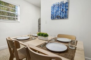 A dining area with a wooden table set for four, including plates, cutlery, and glasses.