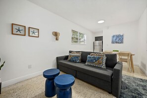 A modern living room with a grey sofa, two blue stools, and decorative pillows. - GROVE27-02 | soothing vibes near chic neighborhood (Miami)