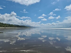 Enjoy a serene beach experience with a wide, smooth shoreline and breathtaking views of distant mountains.