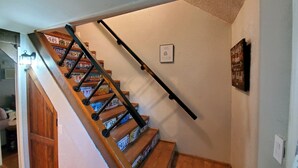 Una escalera de madera con barandales negros y un cartel en la pared.