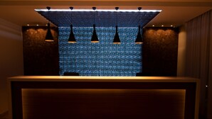 Un mostrador de recepción con pared azul texturizada e iluminación colgante.