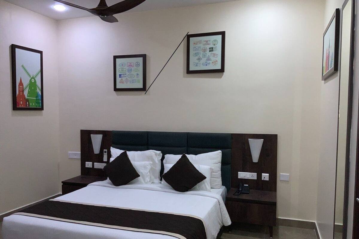 A hotel room with a bed, bedside tables, a ceiling fan, and framed artwork on the walls.